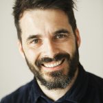 Portrait of a bearded man smiling at the camera.